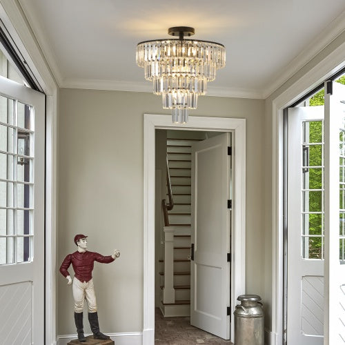 Chandelier hanging in a room with a staircase and decorative figure on the wall.