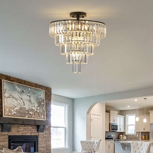 Chandelier hanging in a living room with a fireplace and kitchen in the background.
