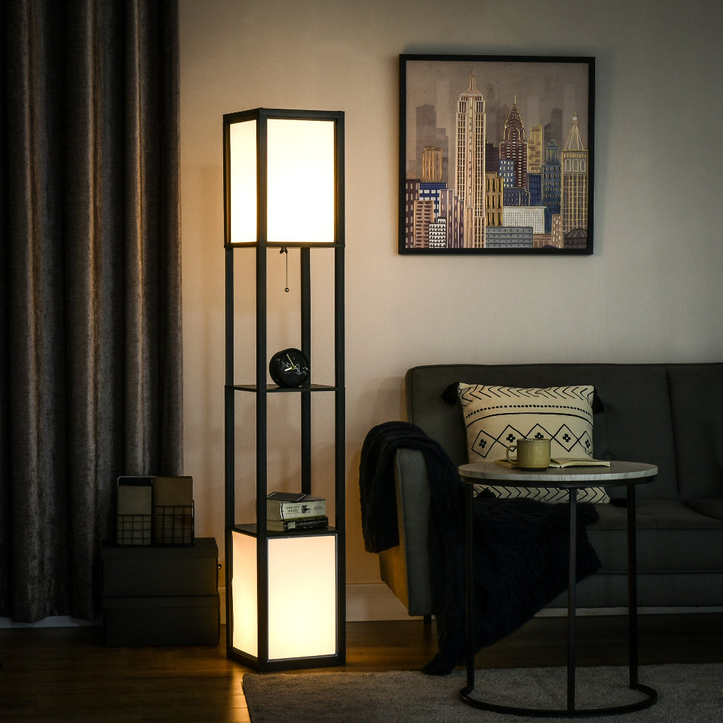 A tall black metal floor lamp with three illuminated white rectangular light panels, styled in a modern living room next to a gray sofa and a round side table.